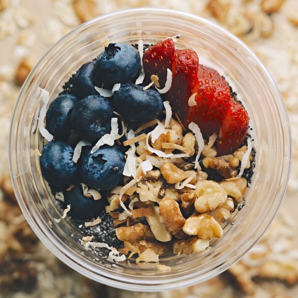 Overhead view of a vegan parfait with blueberries, strawberries, walnuts, and shredded coconut.