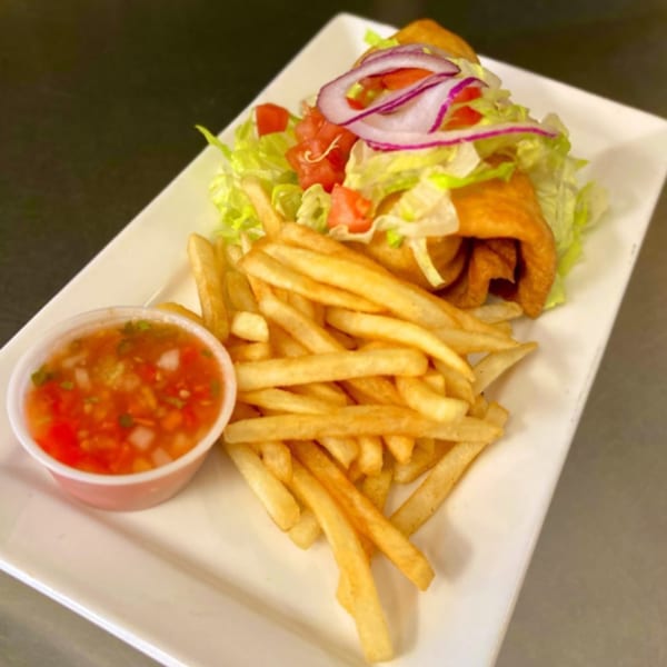 Vegan chimichanga topped with lettuce, tomato, and red onion, served with fries and salsa.